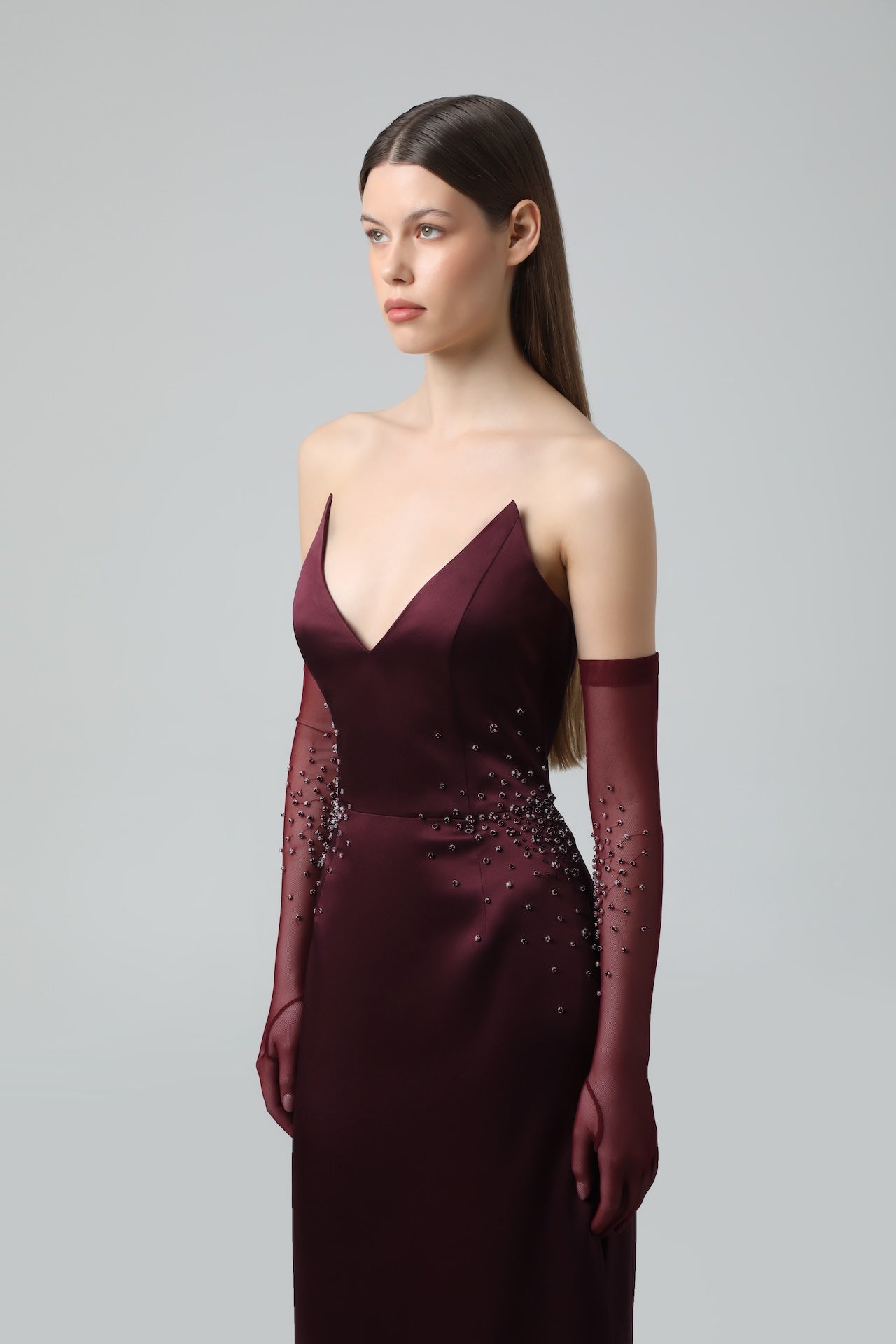 Model wearing burgundy crystal mesh gloves styled with matching gown, elegant evening look.