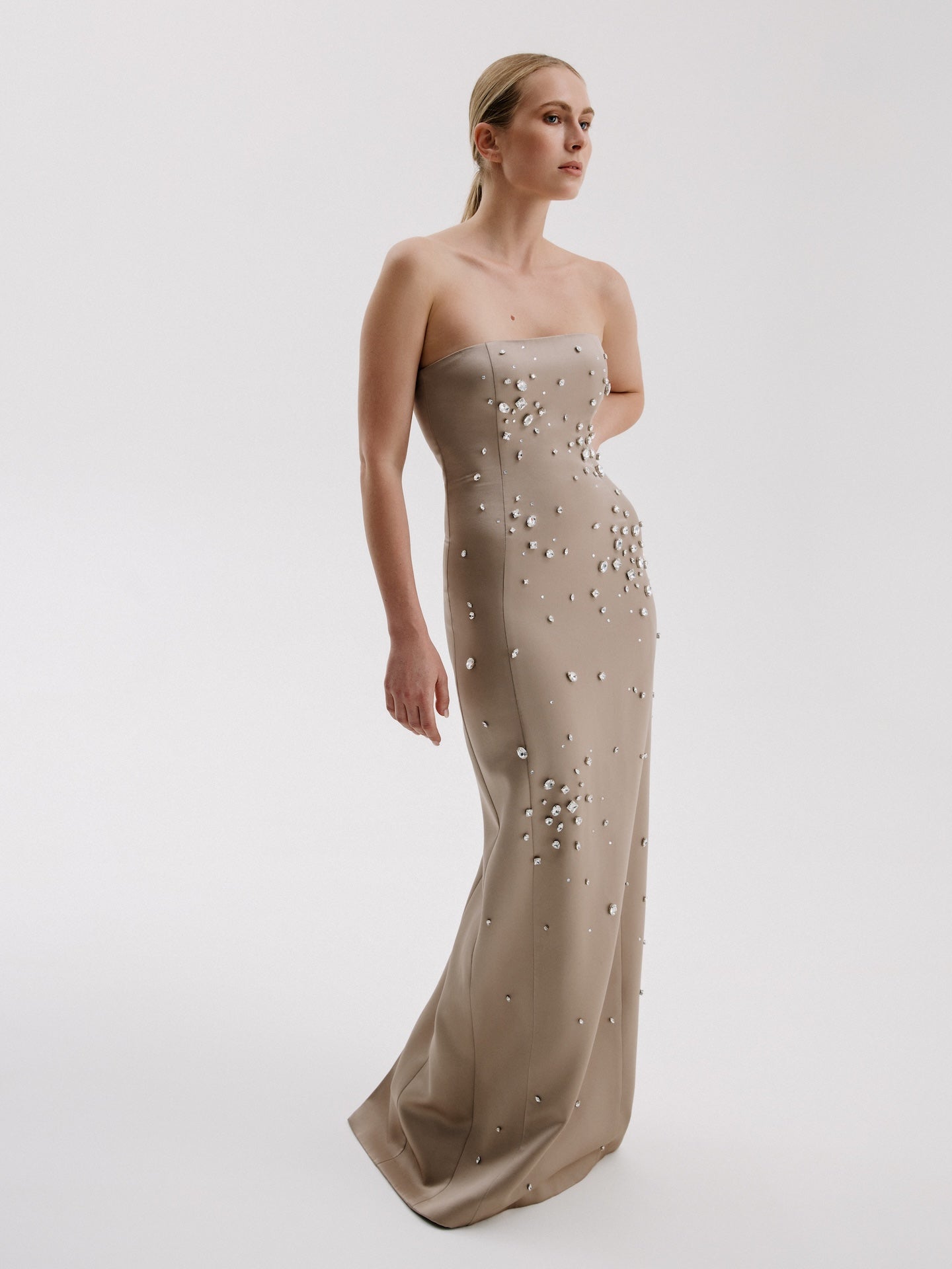 Side view of crystal-embellished champagne evening gown for formal occasions.
