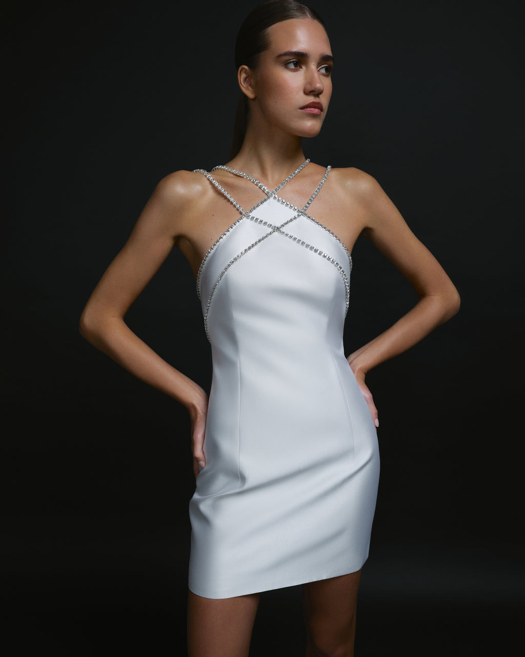 Model wearing white mini dress with crystal straps and open back.