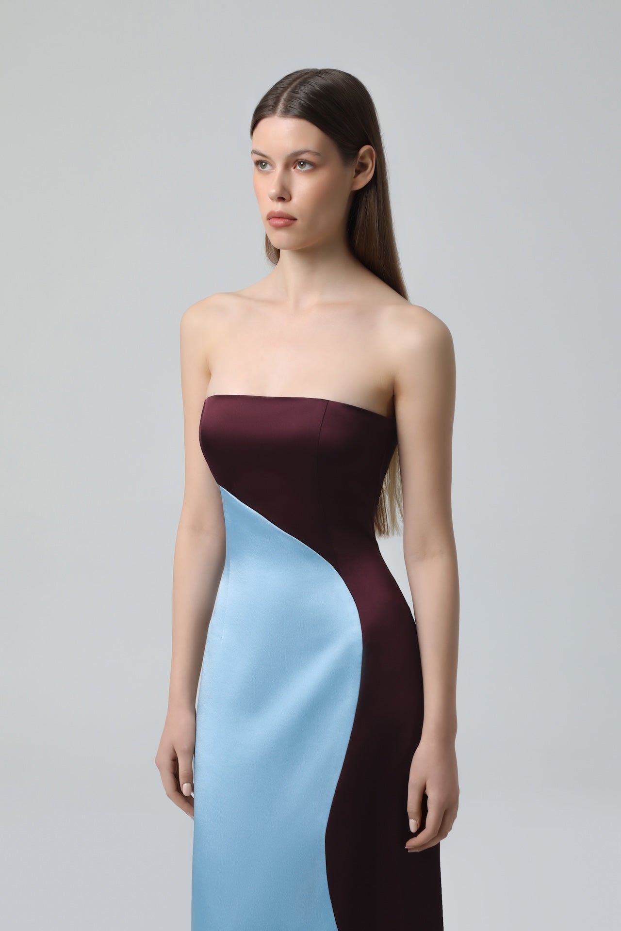 Model wearing NDS The Label two-toned strapless satin maxi dress in blue and wine, close-up front view.